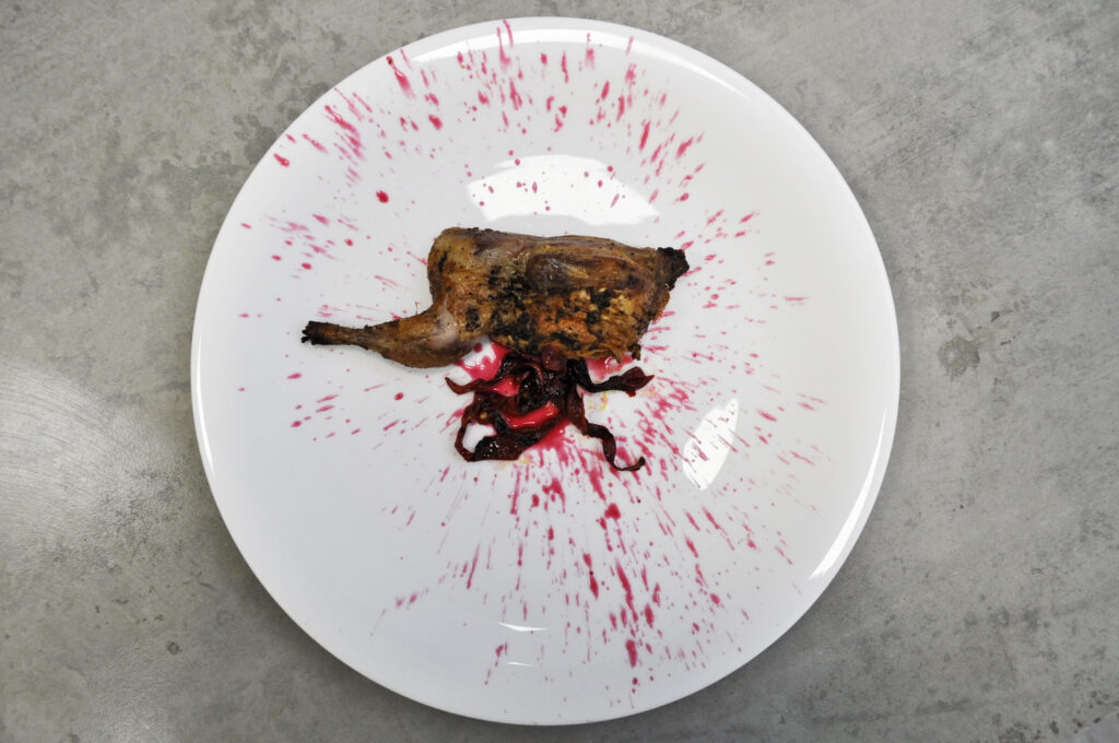 una cordoniz especiada emplatada inspirada en halloween con caldo de pollo con colorante rojo simulando sangre