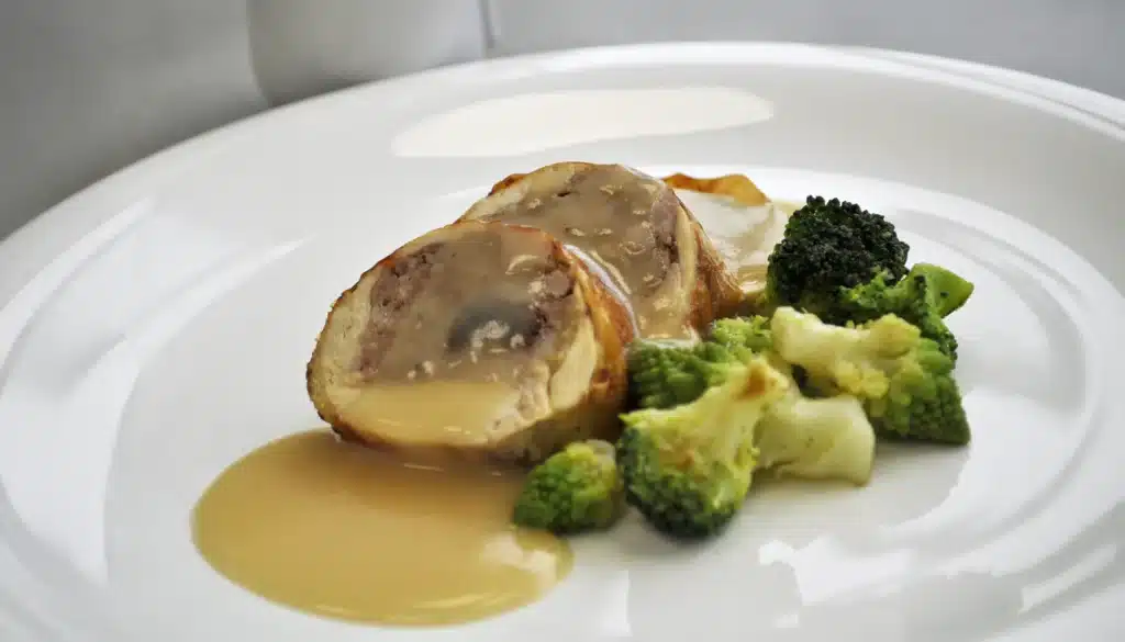 Un plato con Pollo coquelet relleno de carne con pasas