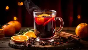 Una taza de Vino especiado navideño con especias alrededor: canela en rama, anís estrellado y clavo.