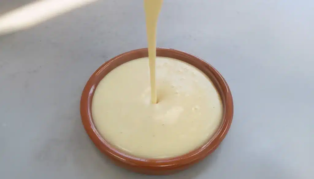 un recipiente en el cual se esta vertiendo preparado para natillas caseras