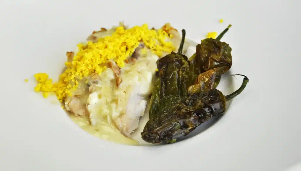 un plato de gallina tiernizada con papaína en polvo acompañada de pimientos del padrón