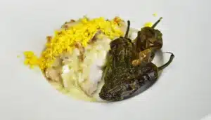 un plato de gallina tiernizada con papaína en polvo acompañada de pimientos del padrón