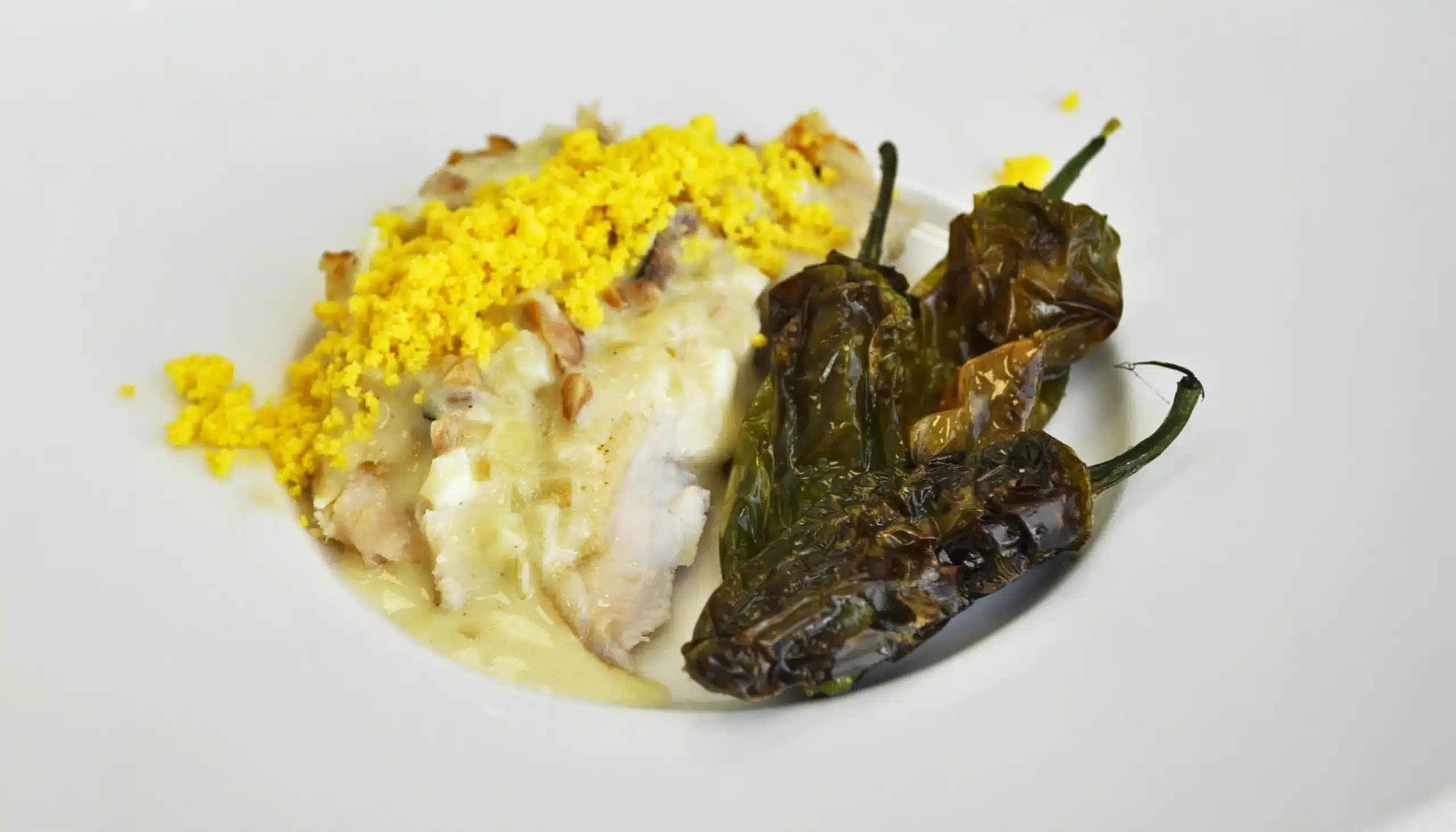 un plato de gallina tiernizada con papaína en polvo acompañada de pimientos del padrón