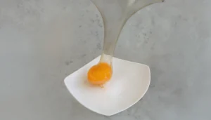 Una yema de huevo encapsulada en una cobertura de isomalt, explicando visualmente la cocina molecular y su inspiración a través de la ciencia culinaria