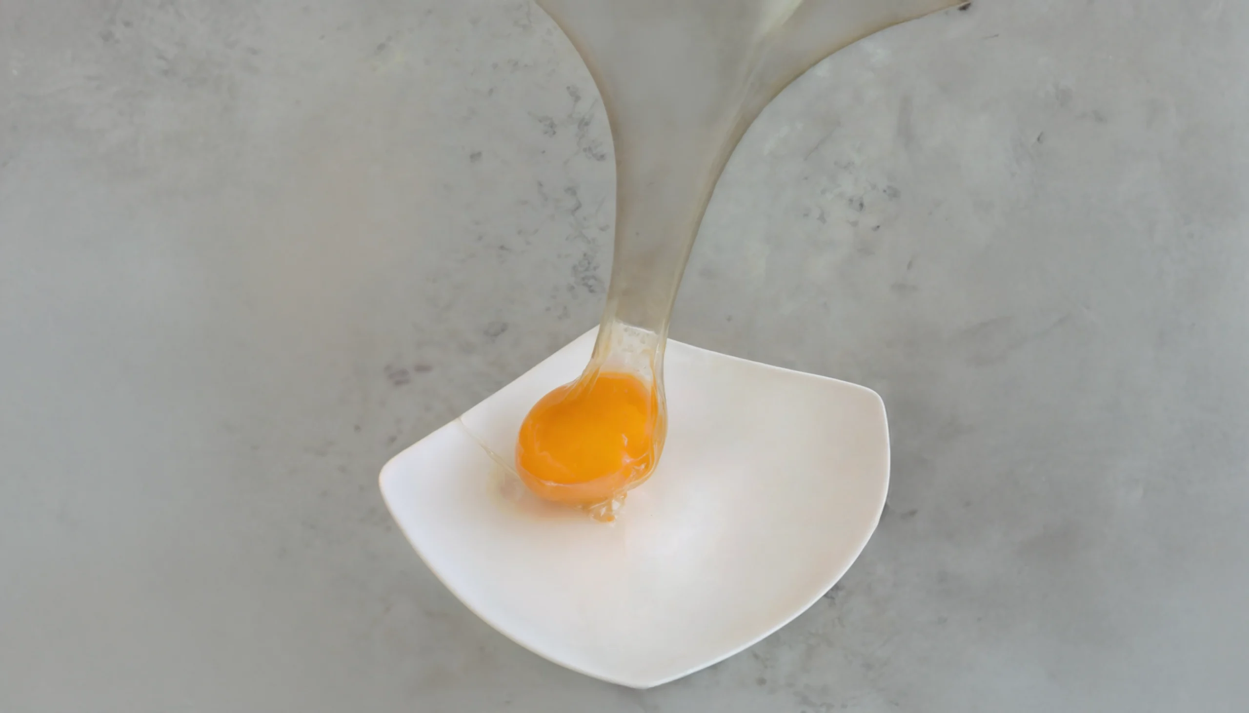 Una yema de huevo encapsulada en una cobertura de isomalt, explicando visualmente la cocina molecular y su inspiración a través de la ciencia culinaria