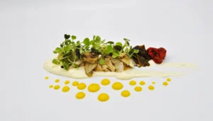 un plato con picanton escabechado con crema y salsa de clementina
