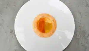 un plato de tartar de gambas y mango con gelatina de dos colores y aire de gamba