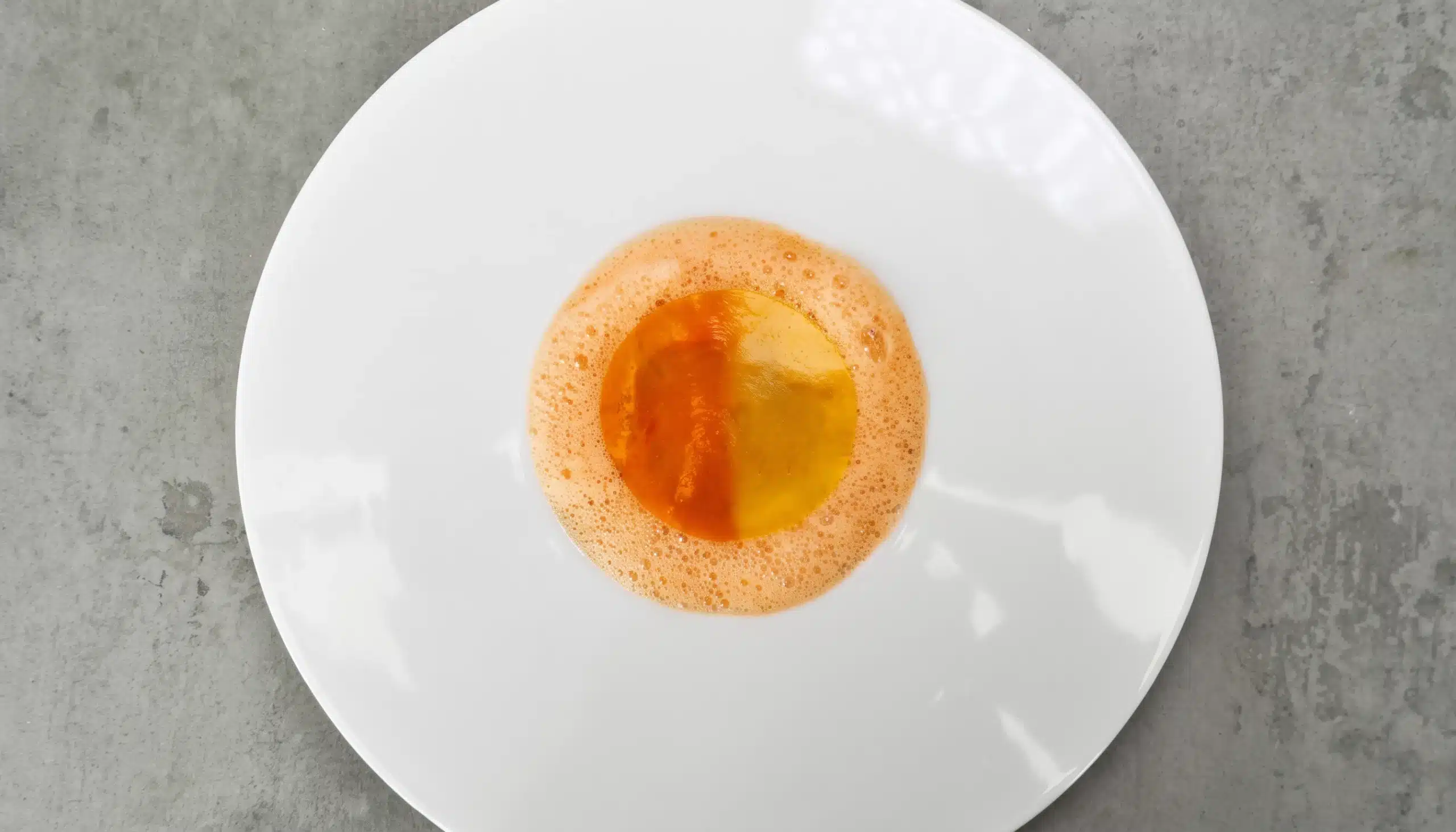 un plato de tartar de gambas y mango con gelatina de dos colores y aire de gamba